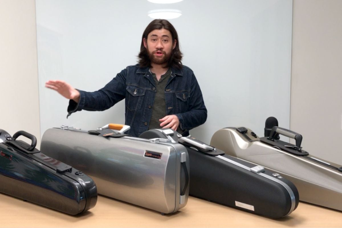A presenter showcasing multiple violin cases arranged on a table