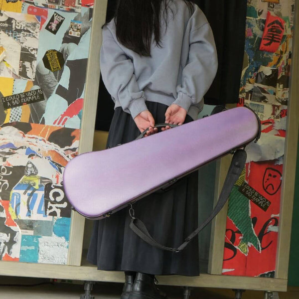 Purple Molto Neo Shaped Violin Case held by a person against a graffiti-collage wall